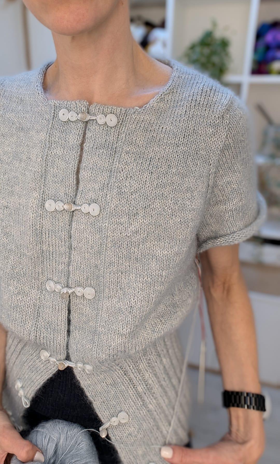 Close-up of the Sordino Cardigan in soft grey with pale frog-knot closures running down the front